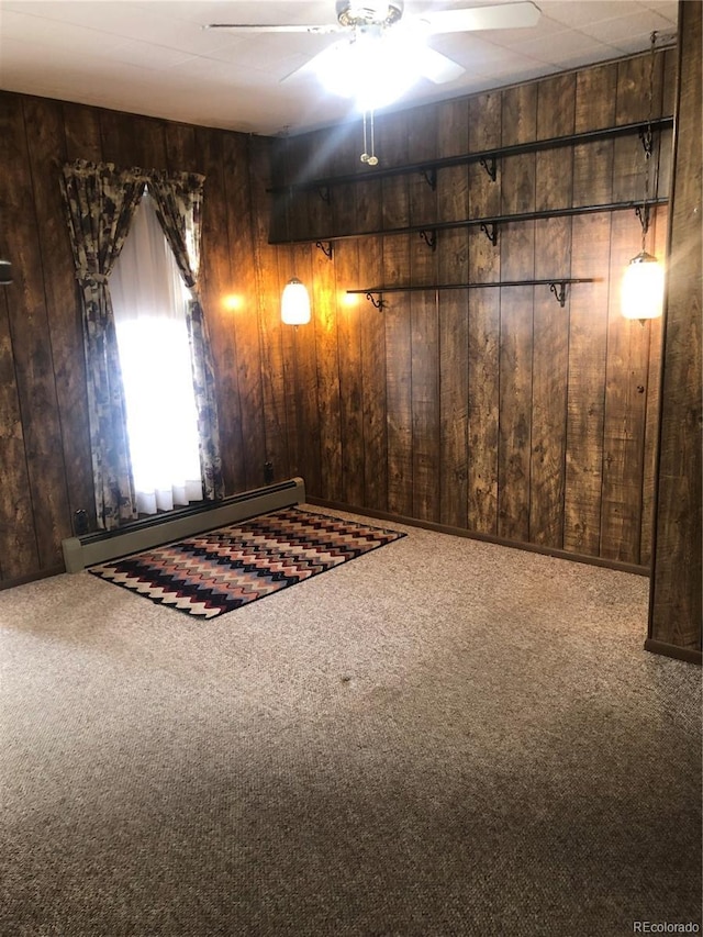 interior space with ceiling fan, carpet flooring, wooden walls, and a baseboard radiator