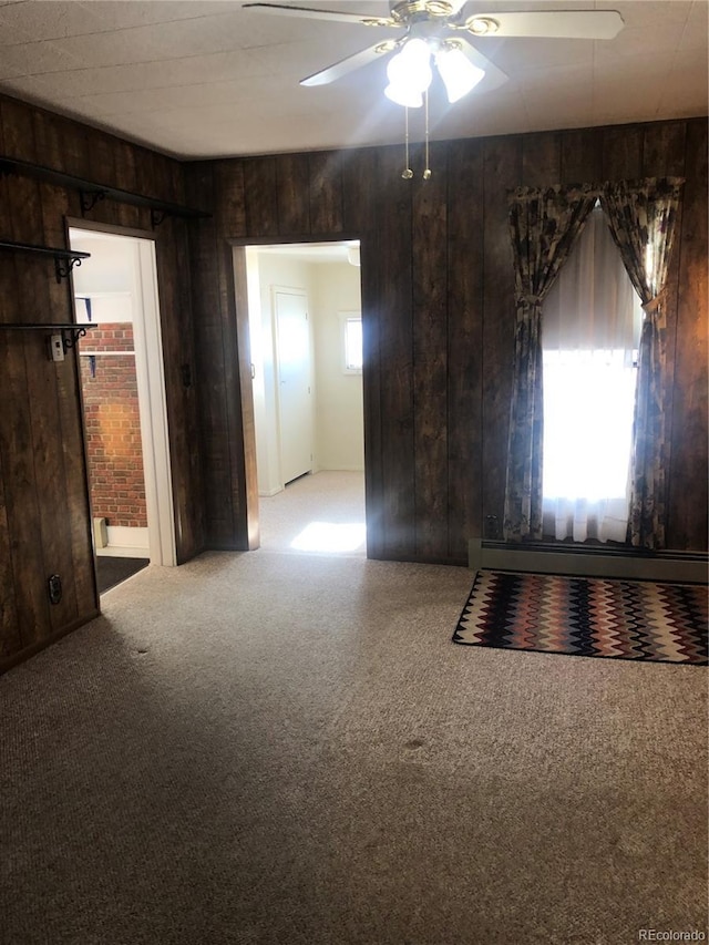 spare room featuring light carpet, wooden walls, and ceiling fan