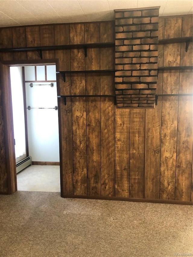 interior space with wooden walls, carpet, and a baseboard heating unit