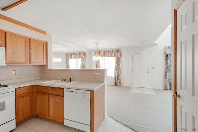 kitchen with white appliances, a peninsula, a sink, light carpet, and a notable chandelier