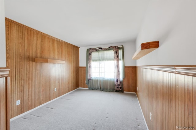 empty room with wainscoting, wood walls, and carpet floors