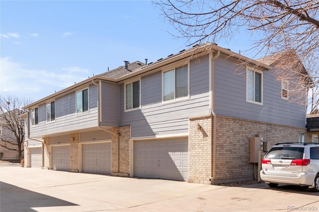 view of front of property featuring a garage, brick siding, and driveway