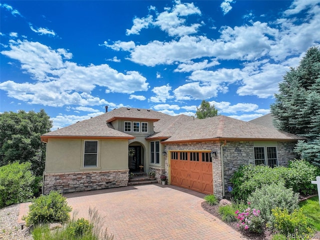 11208 W Ontario Ave, Littleton, CO 80127 - view of front of house with stone siding, stucco siding, an attached garage, decorative driveway, and roof with shingles