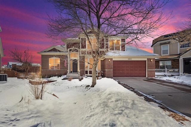 view of front of house featuring brick siding, driveway, and fence