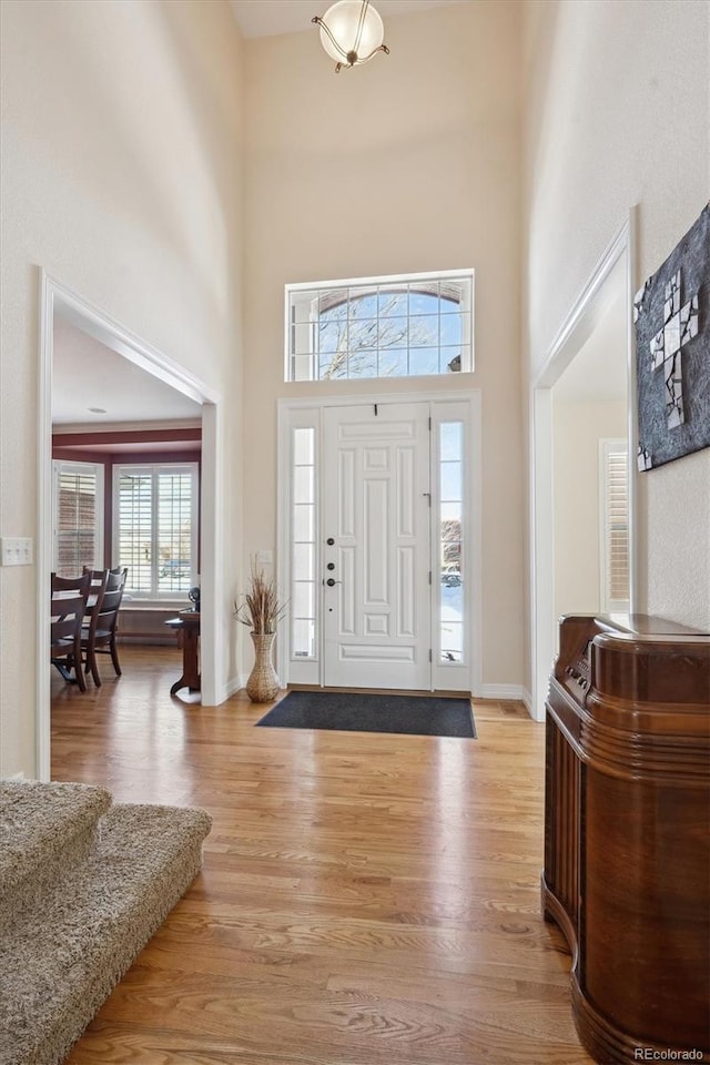 foyer entrance featuring light hardwood / wood-style floors and a high ceiling