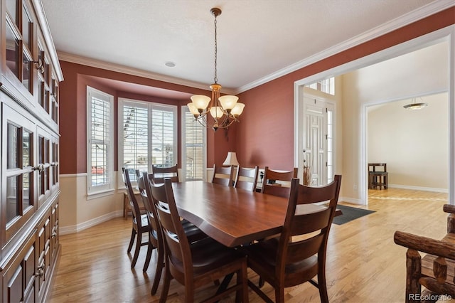 dining area with ornamental molding, a notable chandelier, and light hardwood / wood-style floors