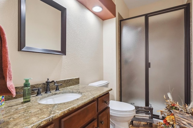 bathroom with vanity, toilet, and a shower with door