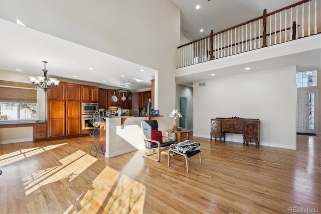 living room featuring an inviting chandelier, light hardwood / wood-style flooring, and a high ceiling