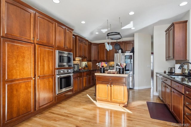 kitchen with sink, a kitchen island, light hardwood / wood-style floors, and appliances with stainless steel finishes