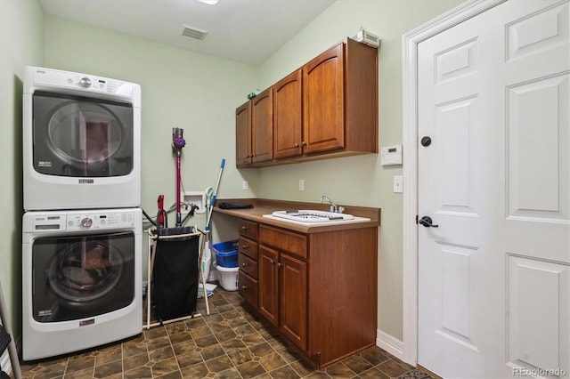 washroom featuring cabinets, sink, and stacked washer and clothes dryer