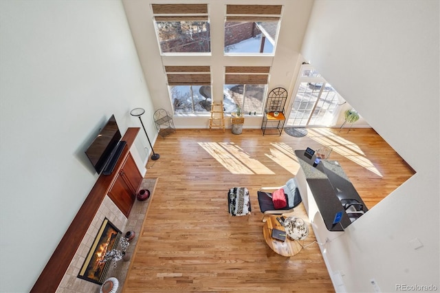 living room featuring hardwood / wood-style flooring, a tile fireplace, and a high ceiling