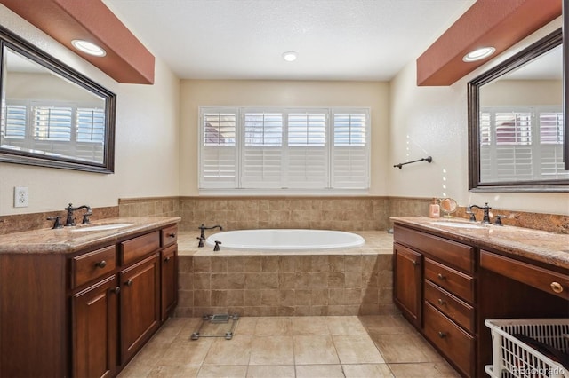 bathroom featuring tiled tub, vanity, and tile patterned flooring