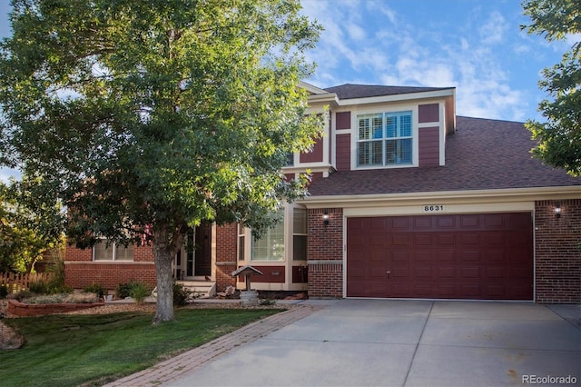 view of front of house with a shingled roof, concrete driveway, an attached garage, a front yard, and brick siding