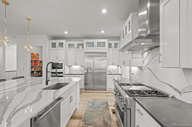 8023 Gore Creek Ln, Littleton, CO 80125 - kitchen with built in appliances, wall chimney range hood, a sink, white cabinetry, and recessed lighting