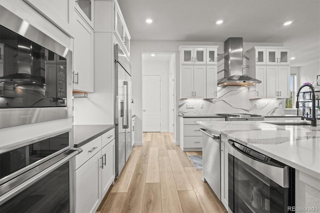 8023 Gore Creek Ln, Littleton, CO 80125 - kitchen featuring wall chimney exhaust hood, built in appliances, a sink, white cabinets, and recessed lighting