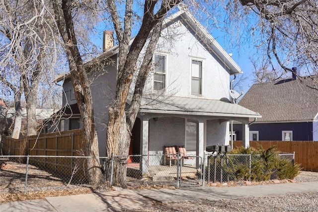 view of front of property with covered porch, a fenced front yard, a gate, and stucco siding