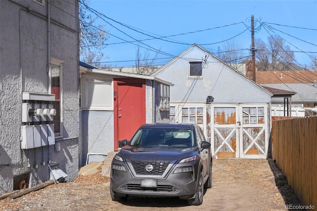 exterior space with stucco siding, an outdoor structure, and fence