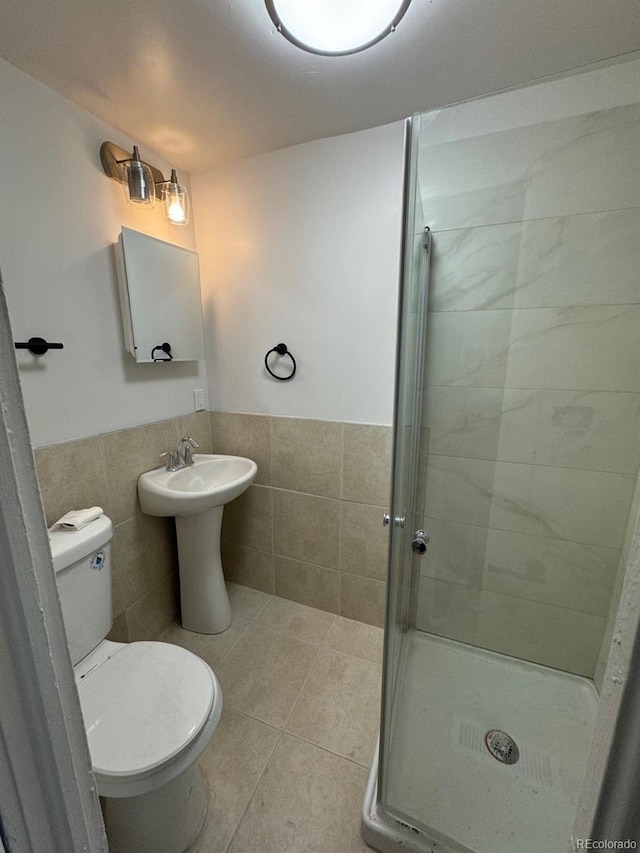 full bathroom with toilet, tile walls, wainscoting, tile patterned floors, and a stall shower