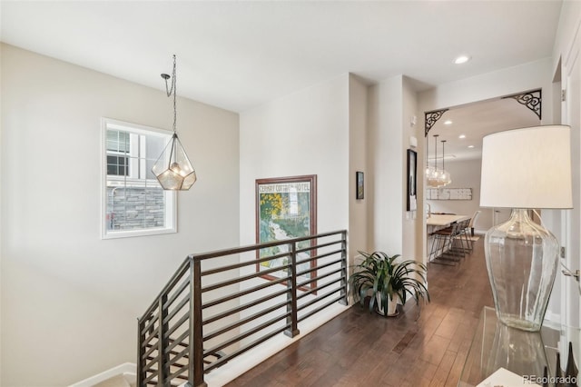 corridor with recessed lighting, a notable chandelier, hardwood / wood-style floors, and an upstairs landing