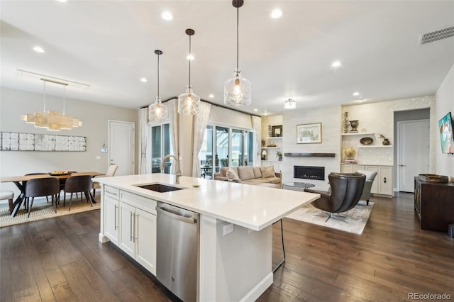 kitchen with sink, white cabinetry, hanging light fixtures, dishwasher, and a kitchen island with sink