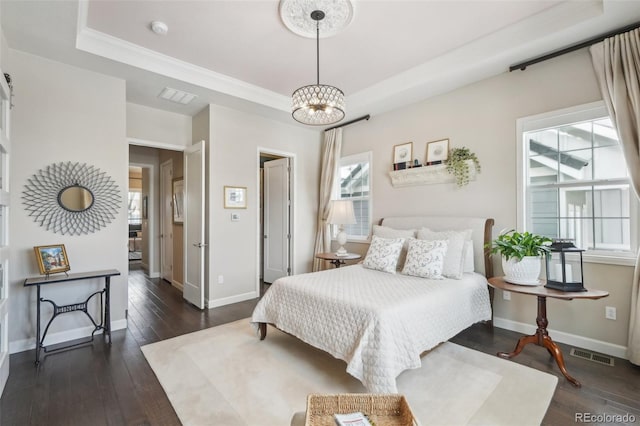 bedroom with a raised ceiling, dark hardwood / wood-style floors, and a chandelier