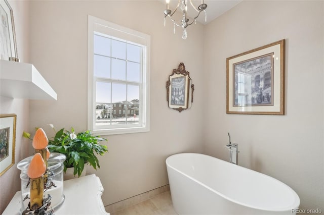 bathroom with tile patterned floors, a tub to relax in, and a chandelier