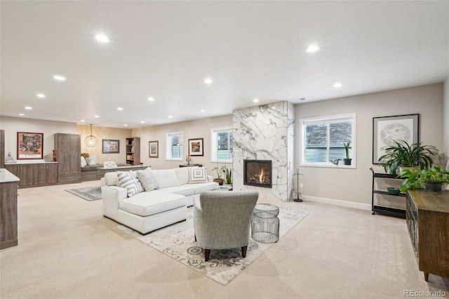 living room featuring plenty of natural light, a premium fireplace, and light carpet