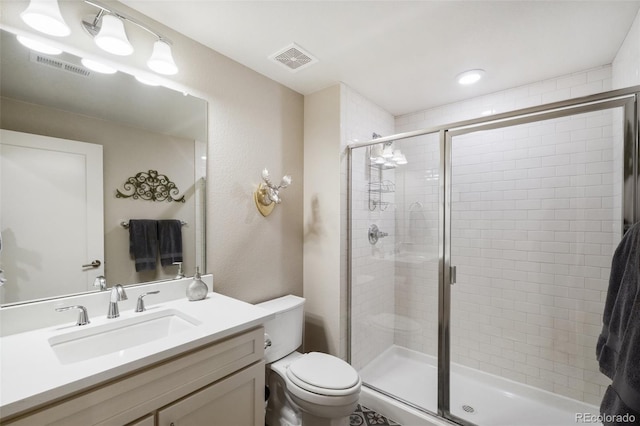 bathroom featuring vanity, toilet, and a shower with shower door