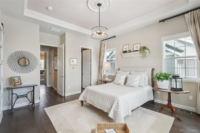bedroom with dark wood-style flooring, visible vents, a tray ceiling, and a notable chandelier