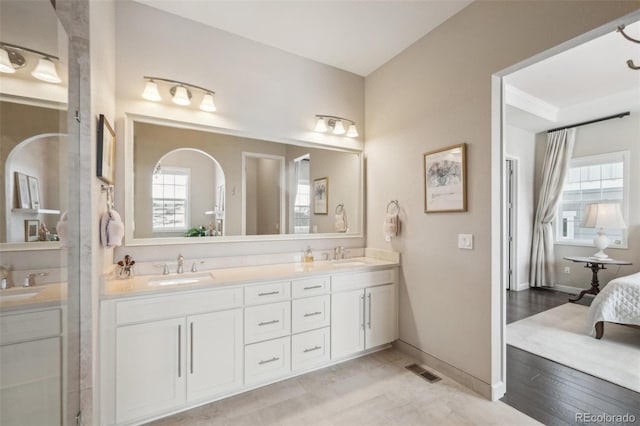 ensuite bathroom featuring double vanity, a sink, and visible vents