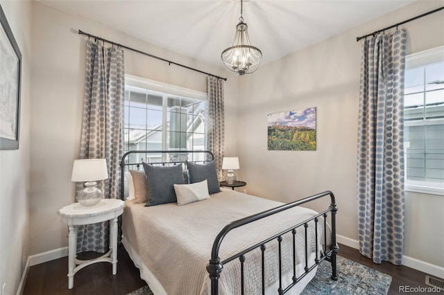 bedroom featuring a notable chandelier, multiple windows, baseboards, and wood finished floors