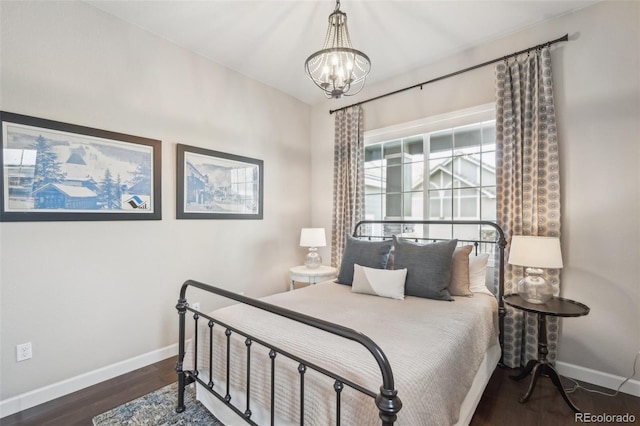 bedroom with wood finished floors, an inviting chandelier, and baseboards