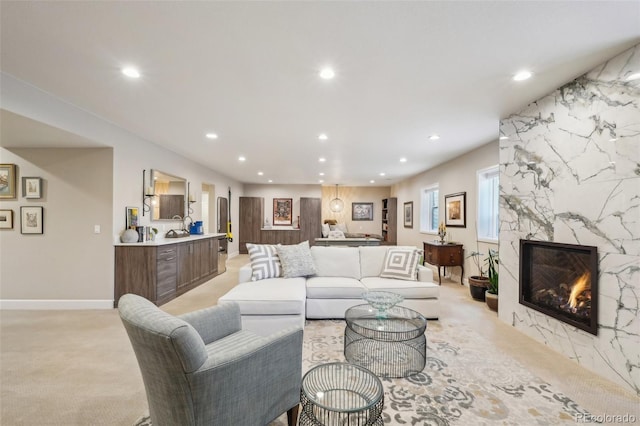 living room with baseboards, recessed lighting, light colored carpet, and a fireplace