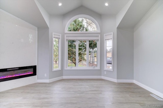 unfurnished living room with high vaulted ceiling and light hardwood / wood-style flooring