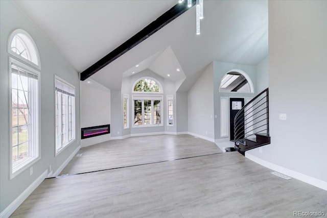 unfurnished living room with vaulted ceiling with beams and light hardwood / wood-style flooring