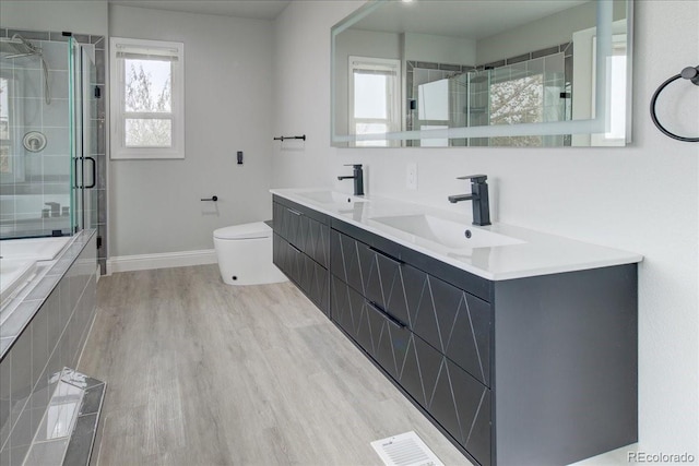 bathroom with hardwood / wood-style floors, vanity, toilet, and a shower with door