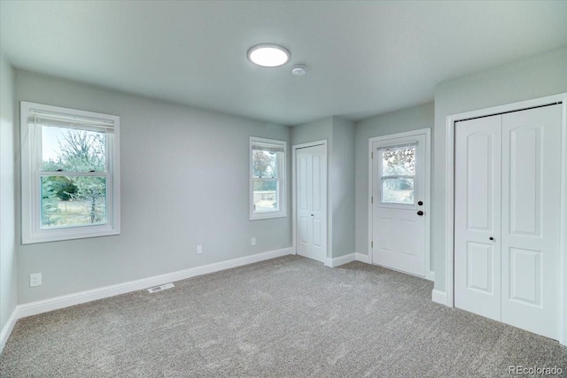 unfurnished bedroom featuring carpet floors, two closets, and multiple windows