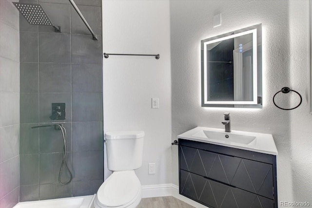 bathroom with a tile shower, vanity, and toilet