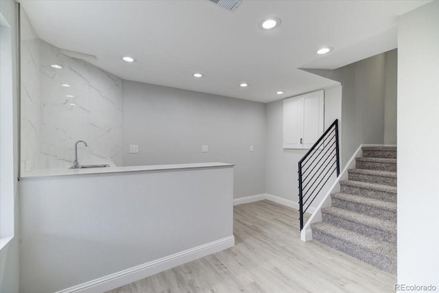 bar with white cabinetry, light hardwood / wood-style flooring, and sink