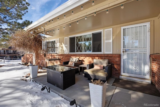 snow covered patio featuring an outdoor living space with a fire pit