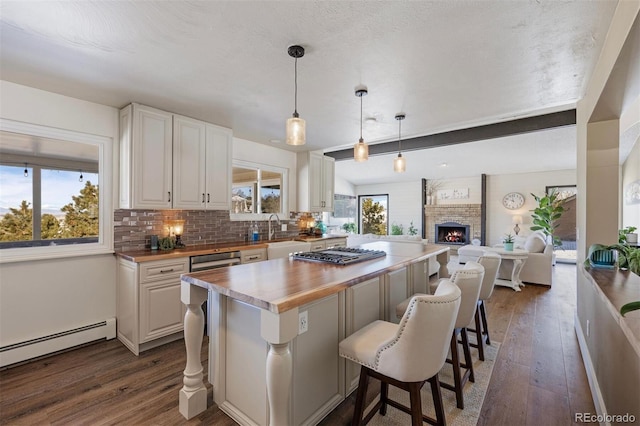 kitchen with a breakfast bar area, white cabinetry, wood counters, decorative light fixtures, and a baseboard radiator