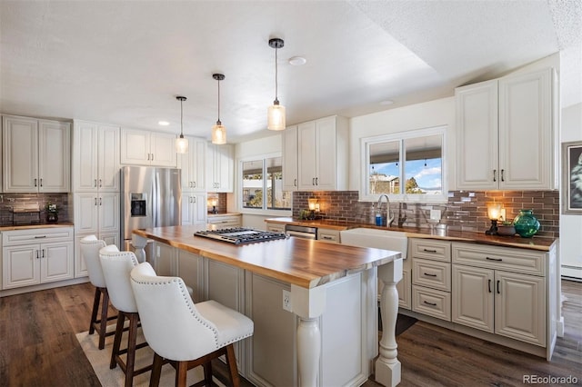 kitchen featuring appliances with stainless steel finishes, butcher block counters, a center island, white cabinets, and a kitchen bar