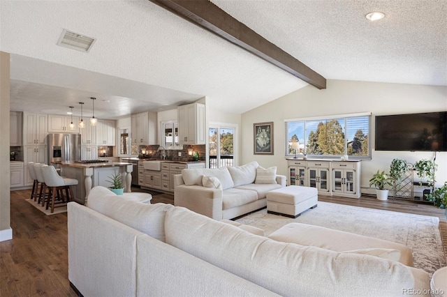 living room with hardwood / wood-style flooring, sink, a textured ceiling, and lofted ceiling with beams