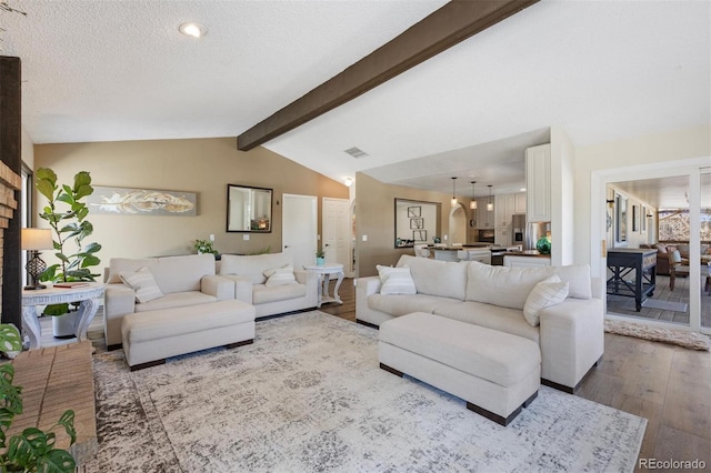 living room with vaulted ceiling with beams, hardwood / wood-style flooring, and a textured ceiling