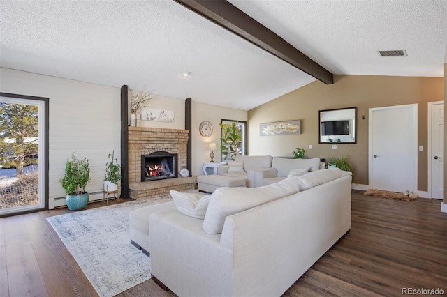 living room featuring dark wood-type flooring, vaulted ceiling with beams, a textured ceiling, a baseboard radiator, and a fireplace