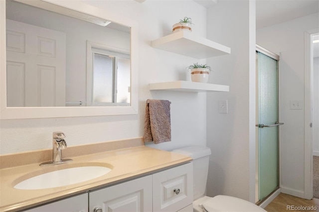 bathroom featuring vanity, toilet, and a shower with door