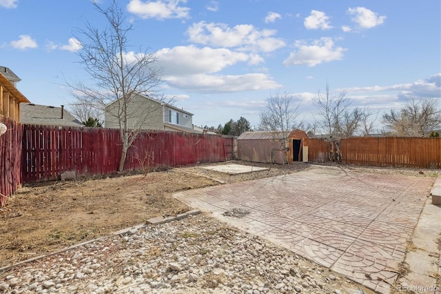 view of yard featuring a storage shed, a patio area, an outdoor structure, and a fenced backyard