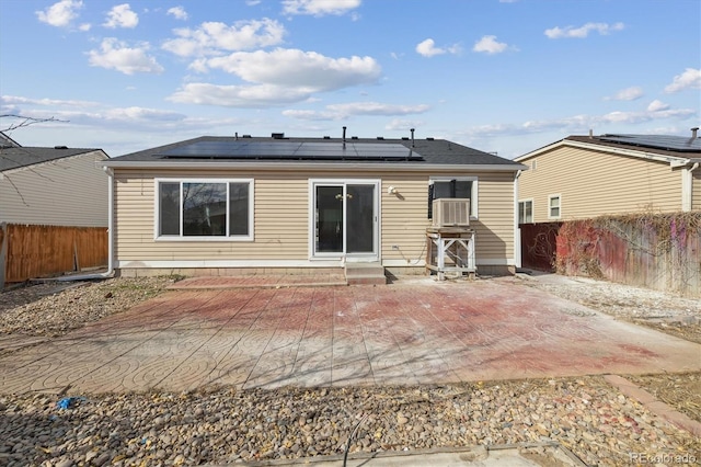 back of house with entry steps, roof mounted solar panels, a patio area, and a fenced backyard