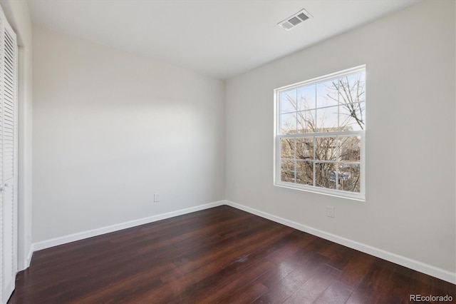 unfurnished bedroom featuring dark wood-type flooring, a closet, visible vents, and baseboards