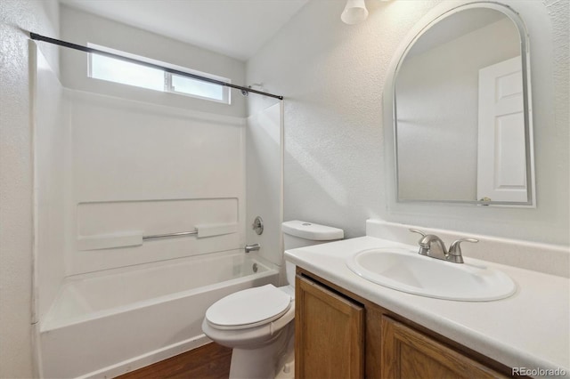 bathroom with a textured wall, toilet, wood finished floors, vanity, and shower / bathing tub combination